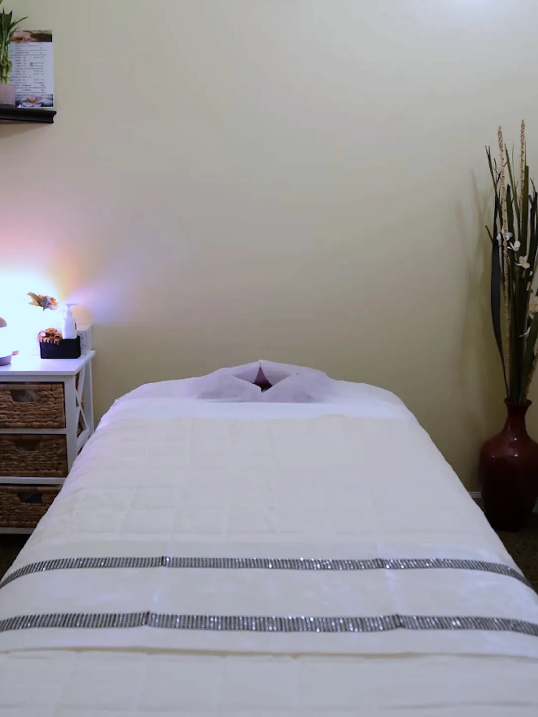 A single treatment room at LJY Reflexology, the table turned down under a warm lamp